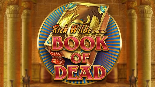 A imagem apresenta o logótipo de “Rich Wilde and the Book of Dead”, com um livro dourado com símbolos egípcios antigos, sobre um fundo circular azul e dourado com colunas de templos ornamentados como pano de fundo.